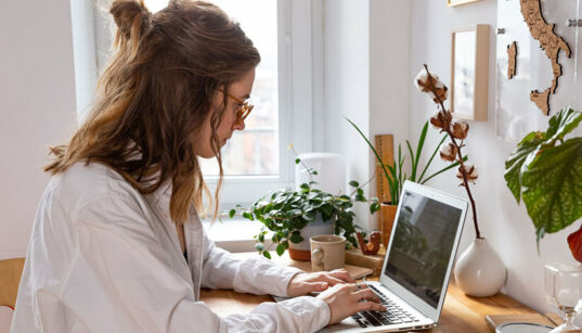 Junge Frau am Laptop. Vielleicht testet sie KI in der Kreativbranche.