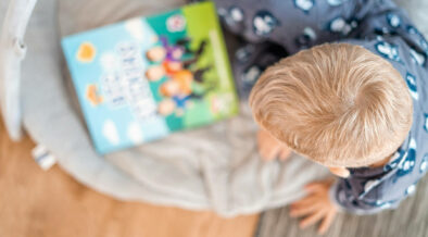 Blick auf einen Jungen, der auf Kinderbücher schaut – aus der Vogelperspektive.