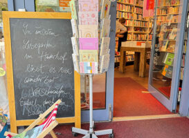 Eingang einer Buchhandlung mit Hinweisschild auf den Lesegarten im Hinterhof in Hamburg-Ottensen.