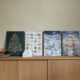 Vier Foto-Adventskalender der kartenmacherei stehen nebeneinander auf einer Holzkommode.