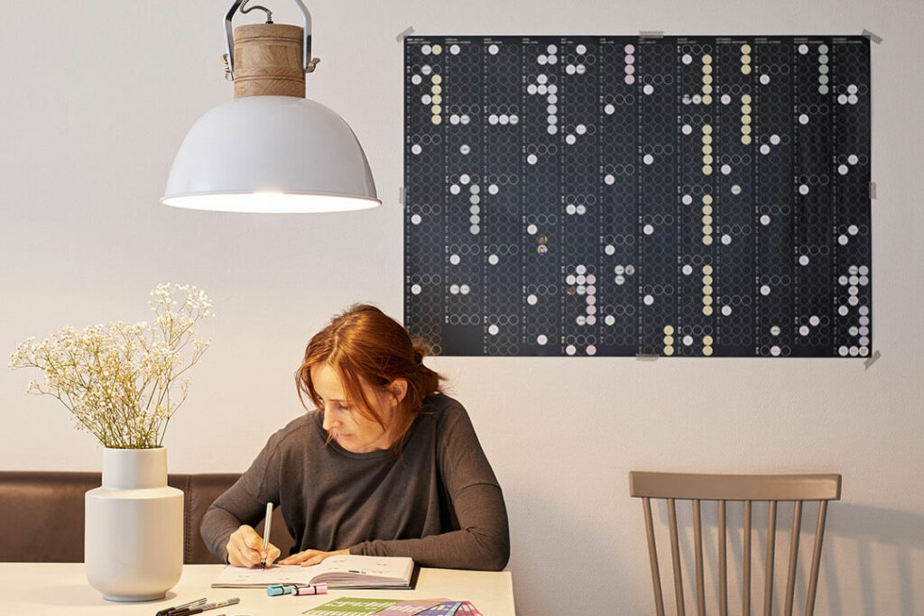 Schwarzer dot-on-Jahresplaner 2027 an einer Wand über einem Schreibtisch