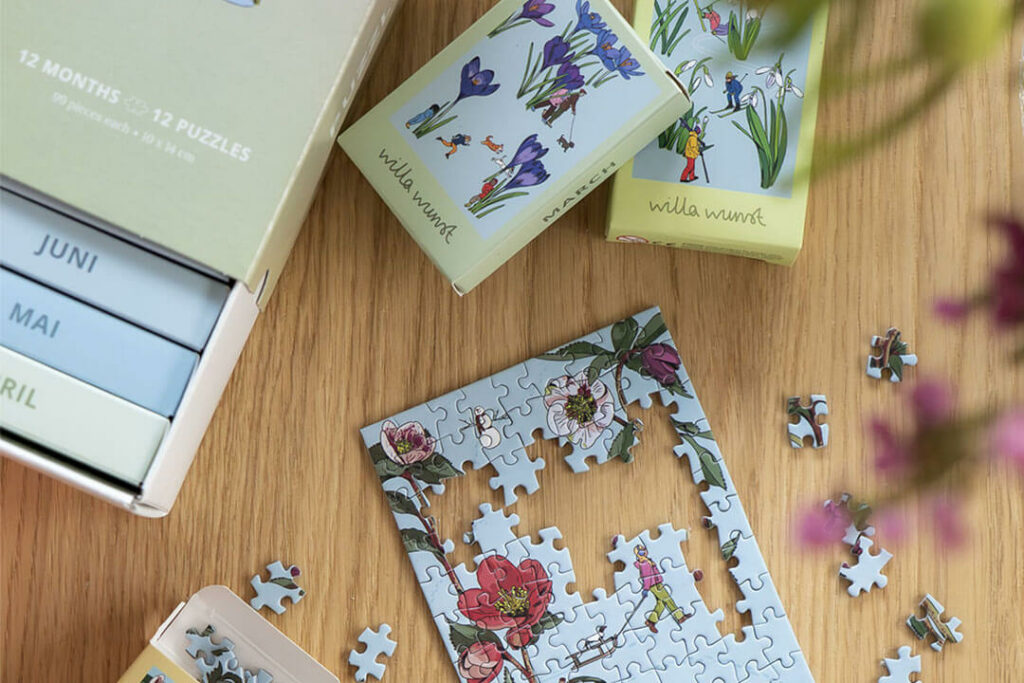 Mini-Puzzle-Kalender von Willa Wunst mit Monatsschachteln und Blumenpuzzle auf einem Holztisch