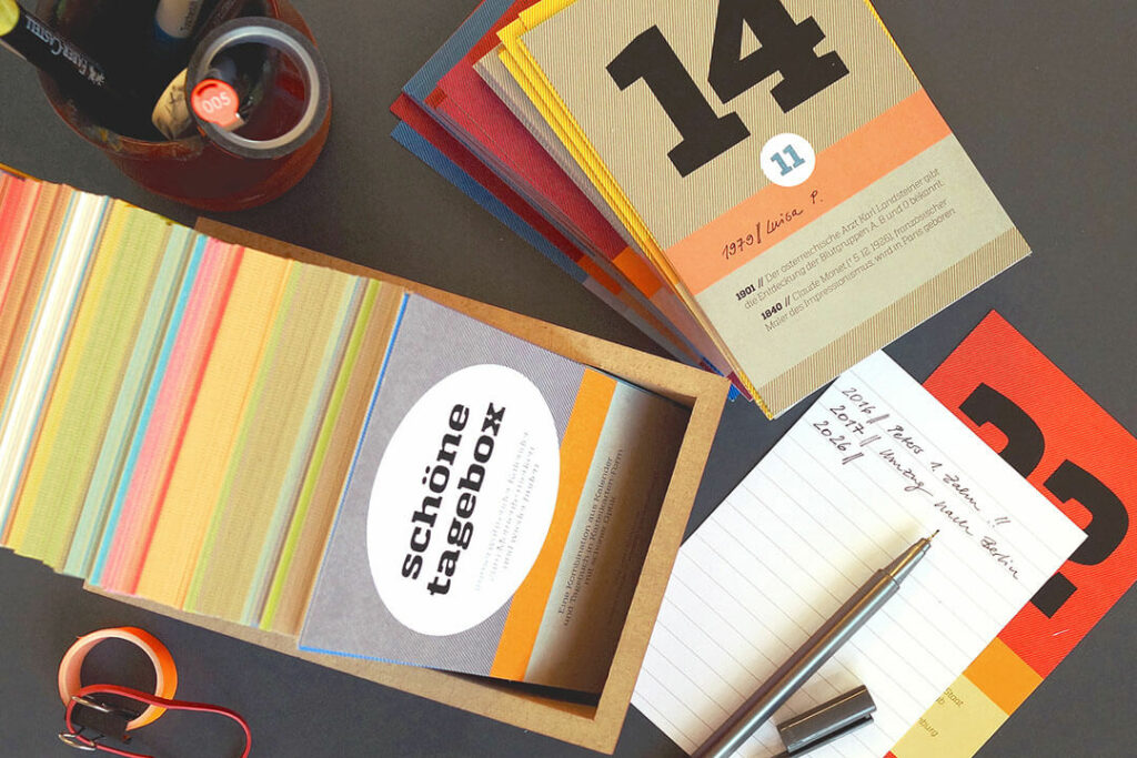 Schönetagebox von sperlingb.design mit bunten Erinnerungskarten in einer Holzbox, handschriftlichen Notizen und Stift
