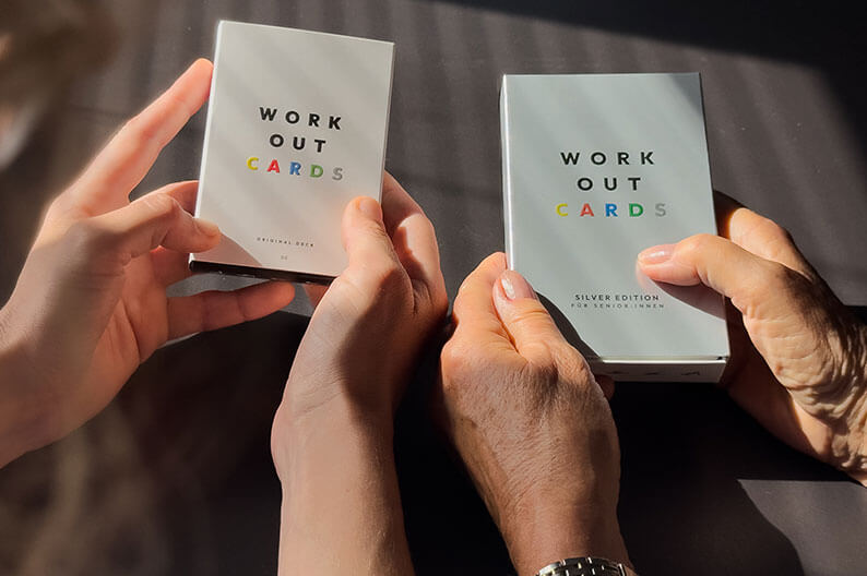 Mehrere Hände halten Kartensets mit Trainingsübungen von Work-Out-Cards.