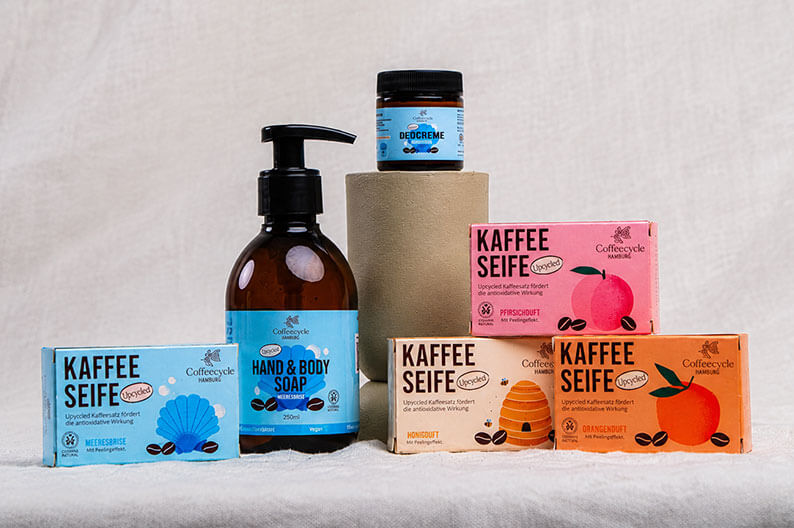 Naturkosmetikprodukte von Coffeecycle in farbigen Verpackungen stehen auf einem hellen Untergrund.