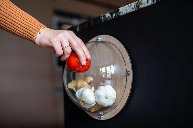 Halbrunder Aufbewahrungsbehälter aus Holz steht auf einem Tisch neben einer Obstschale.