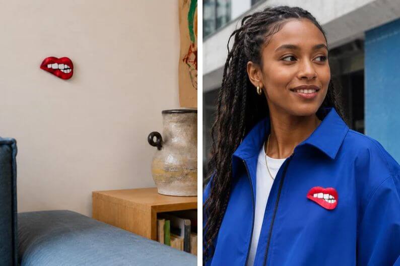 Frau trägt ein kleines rotes Schmuckmotiv aus spiegelndem Acryl an ihrer blauen Jacke.